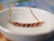 Elegant Hawaiian shell necklace resting in a white ceramic bowl featuring genuine Kahelelani shells in a minimalist curved floating shell necklace design with soft island tones.