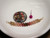 Close-up view of the curved floating shell pendant displayed beside a dime coin and pink head pin for size comparison featuring genuine Kahelelani shells from Niʻihau in ombré green, Keʻokeʻo, red burgundy, and brown tones.