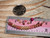 Close-up size comparison photo of genuine Kahelelani shells displayed beside a ruler, dime coin, and pink head pin showing the tiny shell size, natural color variations, and detailed handcrafted workmanship of the floating shell pendant.