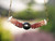 pd_618
Hanging view of a triple strand poepoe Kahelelani shell necklace featuring a round baroque silver tone Tahitian pearl centerpiece surrounded by tightly woven burgundy and brown ombré Kahelelani shells from Kauaʻi showcasing the curved floating design and detailed Hawaiian shell workmanship.