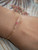bl_705
Island charm Kahelelani shell bracelet worn on wrist featuring genuine Niʻihau shells in soft pink flower, keʻokeʻo, and ʻōmaʻomaʻo green tones accented with delicate 14k gold filled chain. Elegant everyday Hawaiian shell jewelry with refined coastal style and tropical island charm.