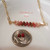 Close-up of handcrafted Hawaiian shell necklace featuring genuine size 11 Kahelelani shells from Niʻihau in ombre shades of off white, pink flower, brown, and rich burgundy displayed beside a dime for size comparison.