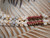 Close-up of the transition between off-white Momi shells and green, pink, brown, and white Kahelelani shells on a traditional 26-inch Niʻihau Kipona shell lei.