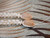 Close-up of the light brown granulated cowrie shell clasp on a traditional Niʻihau Kipona shell lei, finished with genuine off-white Momi shells.