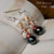 Dainty Niʻihau shell earrings handcrafted in a traditional Pikake style with genuine Momi shells, rare and hard-to-find red Kahelelani shells, peacock semi-round Tahitian pearls, and sterling silver earring hooks.