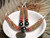 Niʻihau Kahelelani shell necklace and matching earrings displayed in a white dish with a dime for size comparison, featuring ombré shell colors and Tahitian pearls