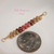 Close-up of tiny genuine Niʻihau Kahelelani shells in green, brown and pink flower colors for a minimalist shell necklace, shown beside a dime for size comparison.