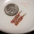 Close-up of minimalist Niʻihau Kahelelani shell earrings #3661 with tiny pink flower and green shells beside a dime for size comparison.