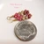 Close-up of dainty Niʻihau shell earrings #3662 laid flat beside a U.S. dime for size comparison, showing the tiny size 10 brown, green and pink Kahelelani shells.