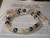 Close-up center section of Niʻihau Momi shell lei #2022 featuring white with red waha, yellow Lenalena and spotted Onikiniki shells with dark Edison pearls showing blue-green iridescent overtones.