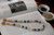 Full display of Niʻihau Momi shell lei #2022 with white, yellow Lenalena, blue Uliuli and spotted Onikiniki shells, dark iridescent Edison pearls and checkered cowrie shell clasp option.