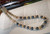 ninl_2024
Angled display of handcrafted Niʻihau Momi Crown Flower shell lei with dark iridescent Edison pearls, Hawaiian shell jewelry
