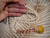 Hand-held view of a Hawaiian Niʻihau shell lei showing the transition from off-white Momi shells to colorful Kahelelani shells and an Oʻahu Sunrise shell pendant.