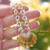 Close-up Niʻihau shell lei pattern with yellow Lenalena blue and off-white Momi, soft pink green Kahelelani and off-white Puka shells