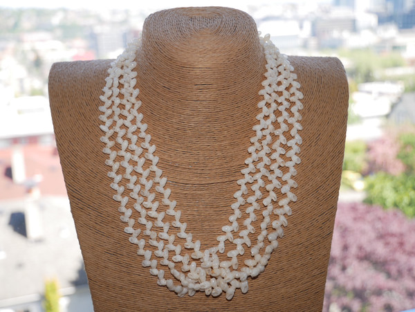 Traditional four strand Hawaiian shell necklace displayed on bust featuring genuine Laiki shells from Niʻihau with flowing layered shellwork and elegant natural off white tones.