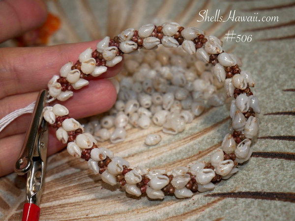 nibl_506
Close up ombre style ʻŪliʻuli Momi shell bracelet shown on hand before adding clasp, featuring rare blue ʻŪliʻuli Momi shells with brown Kahelelani shell accents. Photo highlights the quality of the shells, detailed workmanship, and balanced flow of shell colors and shell sizes throughout the bracelet.