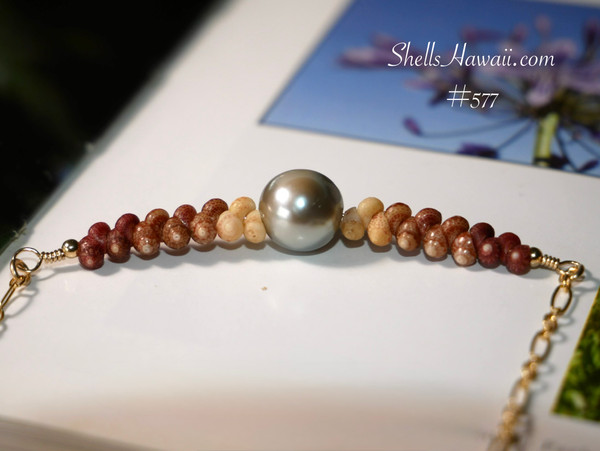 PD_577
A close-up of a 16 3/4" minimalist shell center necklace, showcasing burgundy, chocolate, and off-white Kahelelani shells from Niʻihau surrounding a 5.5 mm Tahitian pearl. This authentic Niʻihau shell jewelry makes for a timeless shell jewelry gift or a rare Hawaiian shell necklace.