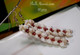 Authentic Niʻihau shells combining off-white Momi and red/burgundy Kahelelani shells, crafted into Heliconia Flower motif. Photographed on neutral background to reflect true shell tones.
