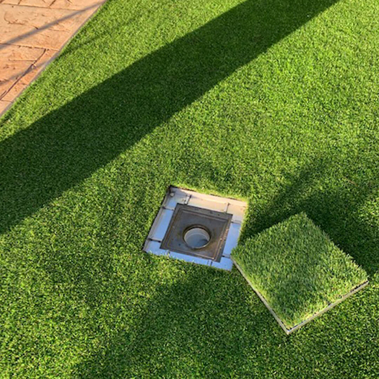 HIDE access cover integrated into turf landscape surface for concealed to drainage and utility systems.
