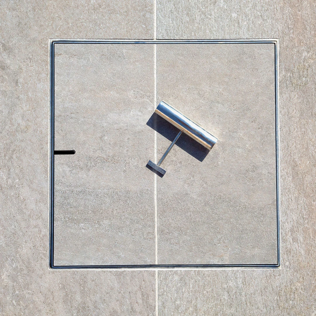 HIDE access cover integrated into pool patio surface for concealed equipment access.
