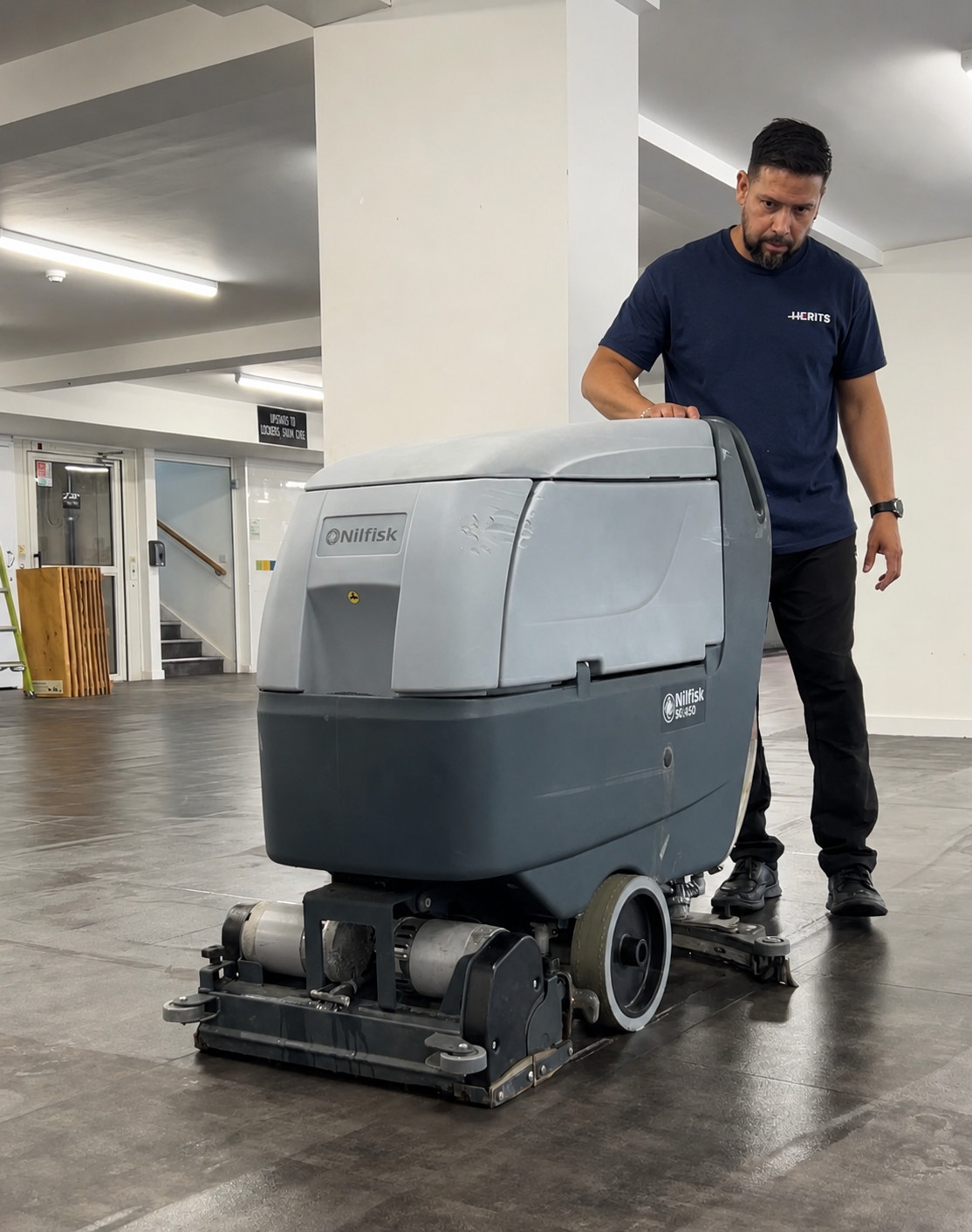 Herits employee operating commercial floor-cleaning machinery