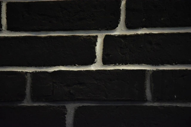 Texture réaliste de vieille brique anthracite avec effets de vieillissement.