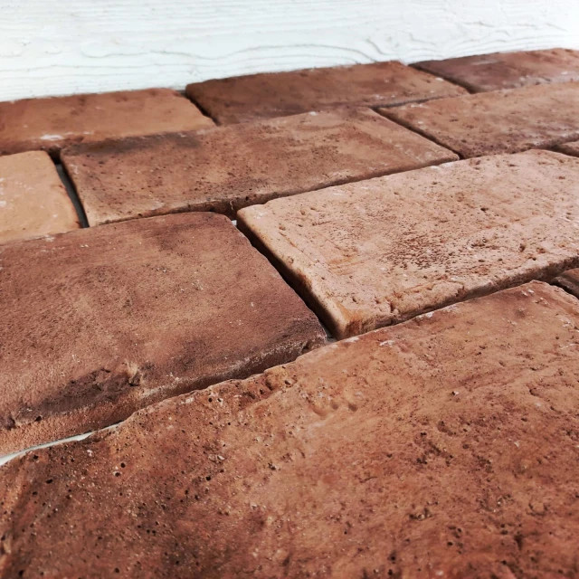 Tuile en céramique brune vieillie, effet brique ancienne, parfaite pour un intérieur rustique.