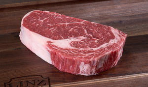 Pictured are 2 uncooked Linz Heritage Angus reserve ribeye steaks on a cutting board