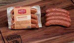 Pictured is a pack of Bauernwurst by Chef Martin next to some fully cooked Bauernwurst on a table.