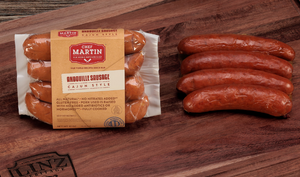 Pictured is a pack of Andouille sausage by Chef Martin sitting next to some cooked andouille sausages on a table.