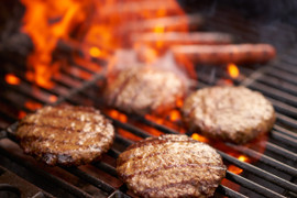 Pictured are four Linz Heritage Angus steak burgers cooking on an open grill.