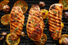 Pictured are 3 cooked chicken breasts on a grill.