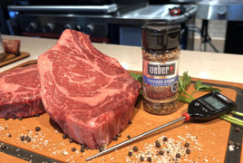 Pictured is an image of an uncooked USDA Prime Bone-In Ribeye, Weber Grill seasoning and a digital thermometer.