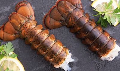 Pictured are 2 cooked Maine lobsters on a slate serving tray