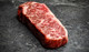 Pictured is 1 uncooked Westholme Wagyu Boneless Strip Steak 14 oz on a cutting board
