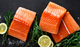 Pictured are uncooked Verlasso Salmon Filets with lemon and herb garnish