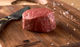 Pictured is an uncooked Prime wagyu Tenderloin Filet from Brush Creek Ranch on a wooden cutting board with a Brush Creek branded knife