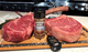 Pictured are 2 uncooked images of 40 oz tomahawks with Weber Grill seasoning and a digital thermometer.