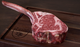 Pictured is 1 uncooked prime dry aged tomahawk ribeye on a cutting board