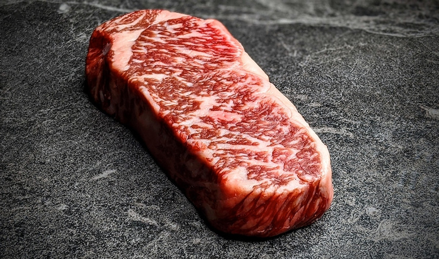 Pictured is 1 raw Westholme Wagyu Boneless Strip Steak 20 oz on a cutting board.