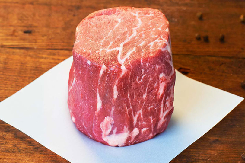 Pictured is an uncooked Linz Heritage Angus barrel cut tenderloin filet wet aged for a minimum of 35 days and finished with a corn feed on a table.