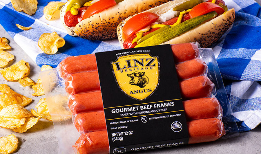 Pictured is a pack of Linz Heritage Angus beef franks on a blue picnic table cloth