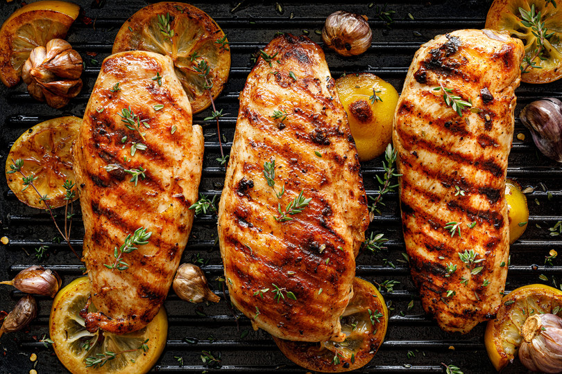 Pictured are 3 cooked chicken breasts on a grill.