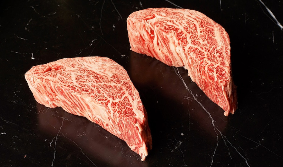 Pictured is 2 uncooked Westholme Wagyu Spinalis Ribeye Cap against a black back drop.