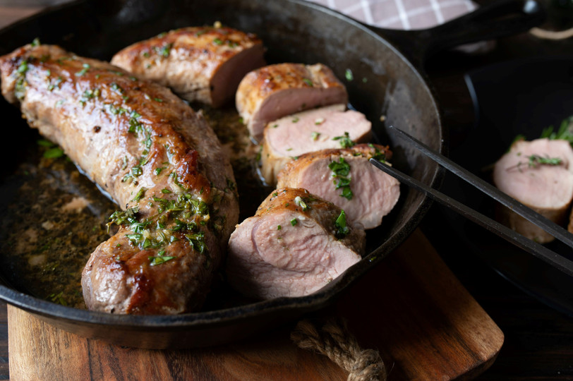 pictured are 2 cooked Duroc pork tenderloins in a frying pan.