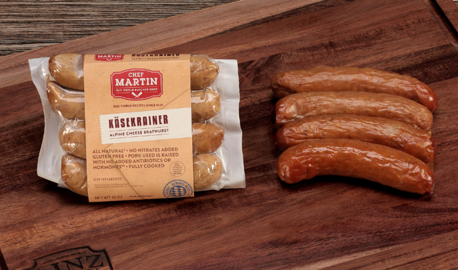 Pictured is 1 pack of Chef Martin Käsekrainer links with some fully cooked links to the side on a table.