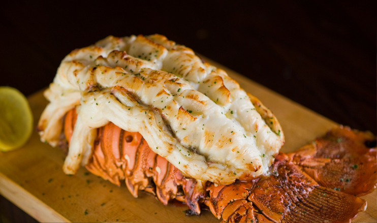 Pictures is a cooked 16-18 oz Maine Lobster Tail on cutting board with lemon garnish