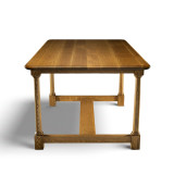 Short side view of White Oak Farmhouse Dining Table showing rounded rectangular top, tapered white oak legs, and lower stretcher base