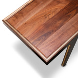 Close-up corner view of solid walnut coffee table showing rich walnut grain, maple inlay detail, and modern framed edge