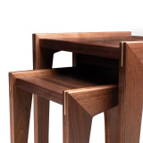 Close-up left detail of modern walnut nesting tables with butcher block walnut tops, mitered legs, and light maple spline accents